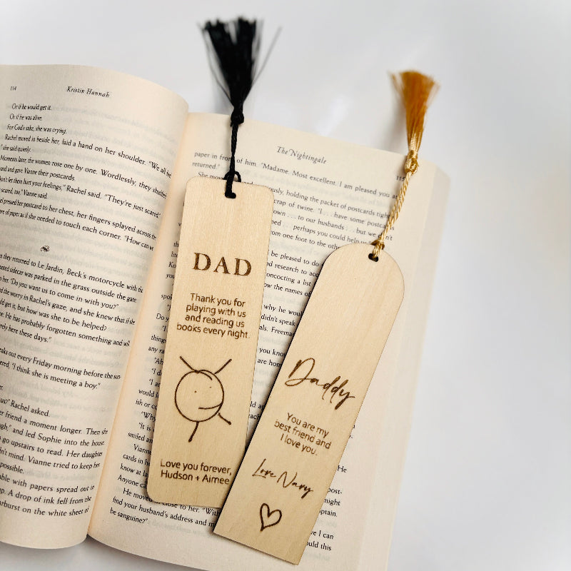 Two wooden bookmarks with engraved messages on an open book.