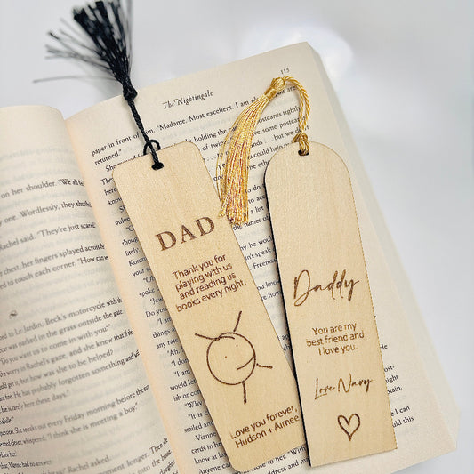 Two wooden bookmarks with engraved messages on an open book.
