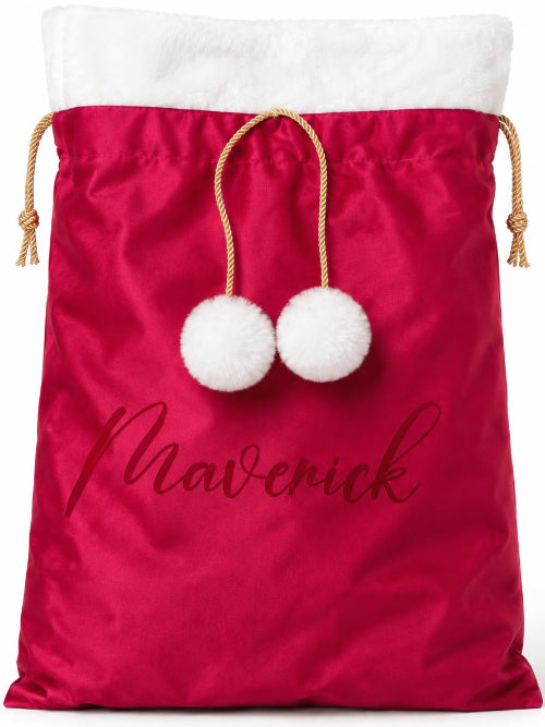 A personalized Christmas Santa sack in bright red satin with a white faux-fur trim at the top, two white pom-poms on gold drawstrings, and the name 'Mavenick' printed in dark red script on the front, shown on a plain white background.